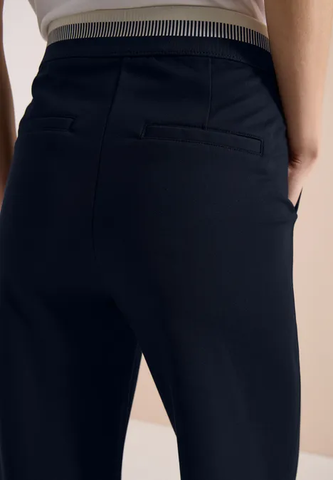 Persoon van achteren in een strakke, zwarte broek met gestreepte elastische tailleband.