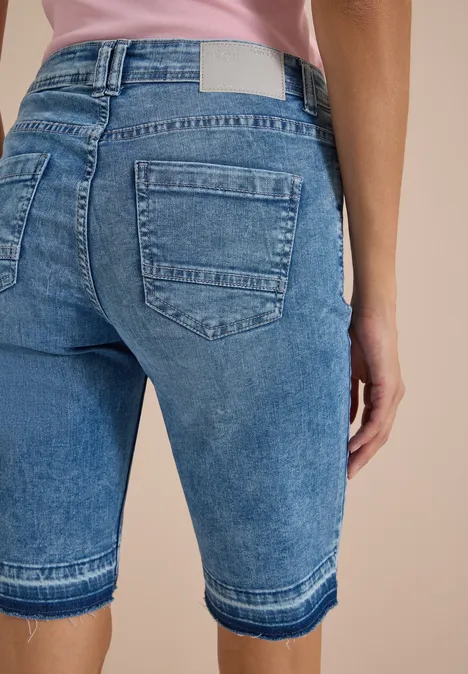 Rückenansicht einer Person in blauen, knielangen Jeansshorts.
