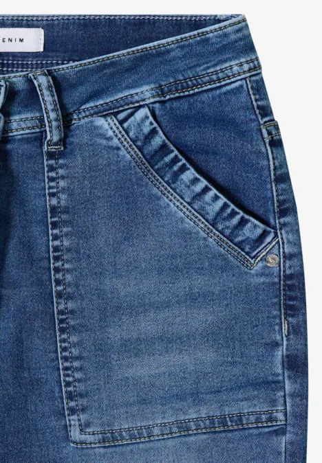Nahaufnahme einer blauen Jeans mit Gürtelschlaufen, Saumnaht und aufgesetzter Tasche.