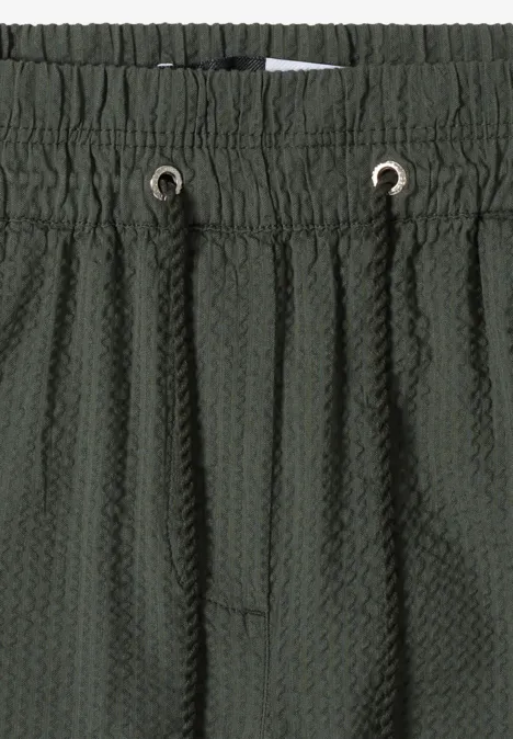 Donkergroene, gestructureerde short met elastische taille, aantrekkoord en honingraatstructuur.