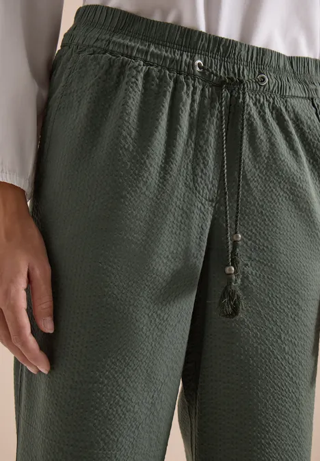 Donkergroene, gestructureerde losse broek met elastische taille en koordsluiting met kwastjes.