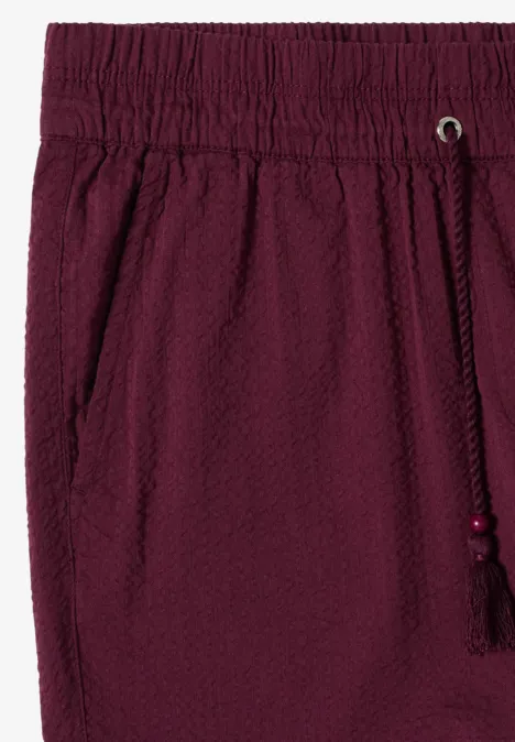 Burgunderrote Shorts aus Seersucker-Stoff mit elastischem Bund, seitlichen Eingrifftaschen und Kordelzug mit Quaste