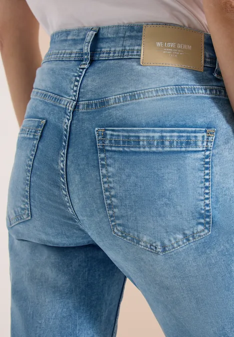 Close-up van een persoon in lichtblauwe jeans, met nadruk op de achterzakken.