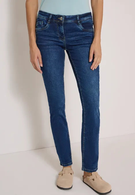 Dunkelblaue Damenjeans in schmaler Passform, getragen mit beigen Loafers.