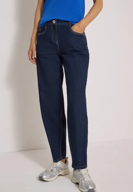 High Waist Barrel Leg Jeans im Loose Fit rinsed wash Dunkelblaue, gerade geschnittene Jeans mit Hosentaschen, kombiniert mit silbernen Sneakers.