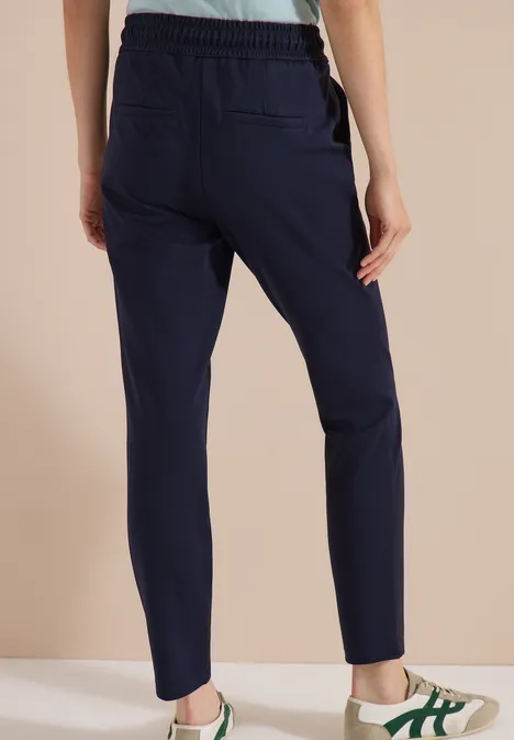 Dunkelblaue, schmale Jogginghose mit Gummizug und Taschen, Modell von hinten.
