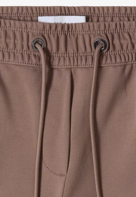 Nahaufnahme einer braunen Hose mit elastischem Bund und Kordelzug.