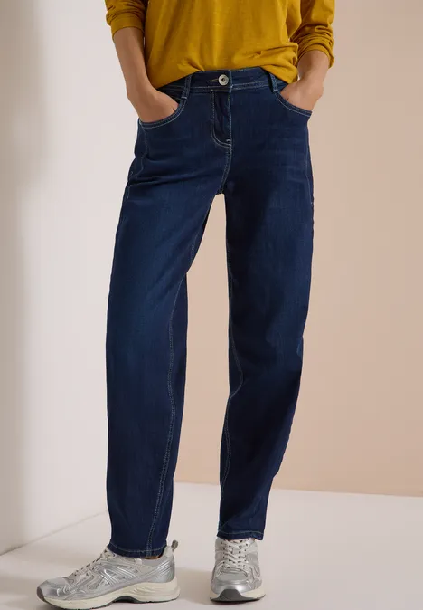 Dunkelblaue Jeans mit geradem Schnitt, aufgesetzten Taschen und silbernen Sneakern.