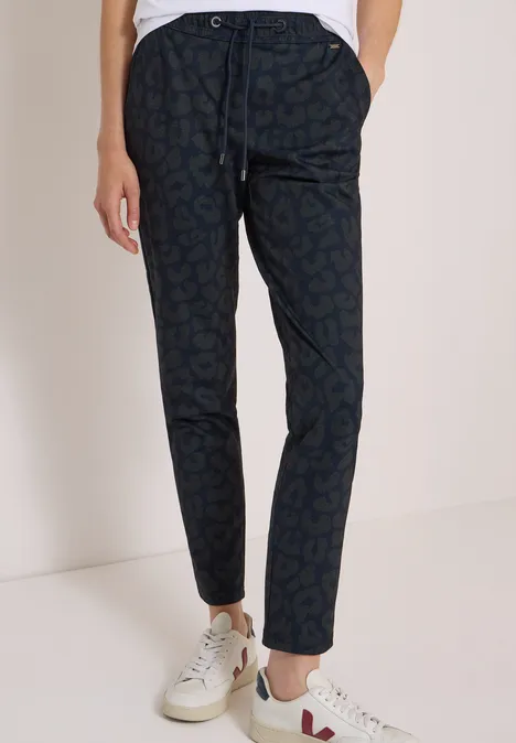 Schmale dunkelblaue Hose mit dezentem Muster, Tunnelzugbund und weißen Sneakern.