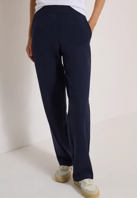 Pantalon bleu marine droit avec poches latérales, porté avec des baskets blanches.