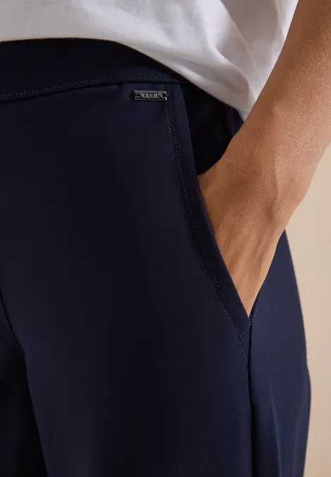 Gros plan d'une personne, main dans un pantalon bleu marine avec une petite étiquette.