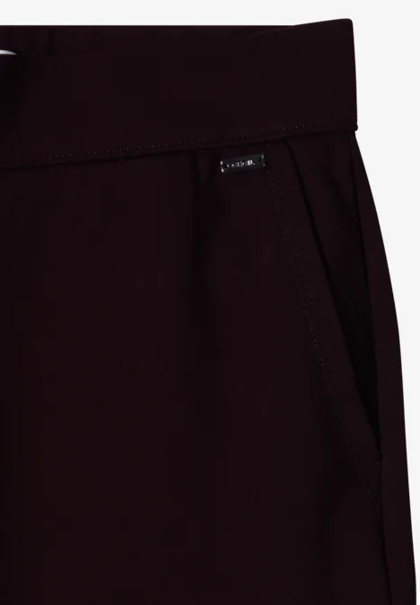 Gros plan sur un pantalon de jogging bordeaux avec poche latérale et petit label