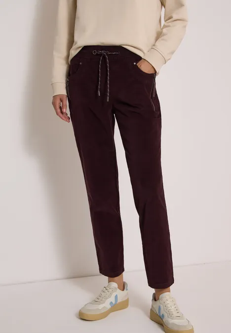 Mid Waist Slim Leg Hose im Casual Fit berry red Bordeauxrote Cordhose mit elastischem Bund, Kordelzug und hellen Sneakern.