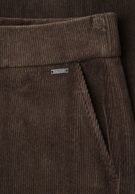 Nahaufnahme einer braunen Cordhose mit seitlicher Tasche und kleinem Metalletikett.