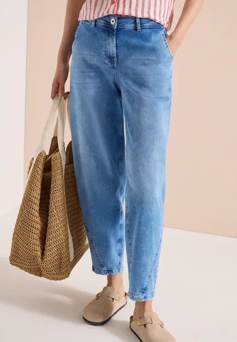 Lichtblauwe jeans met wijde pijpen, gestreept topje, gevlochten rieten tas en comfortabele slip-ons.