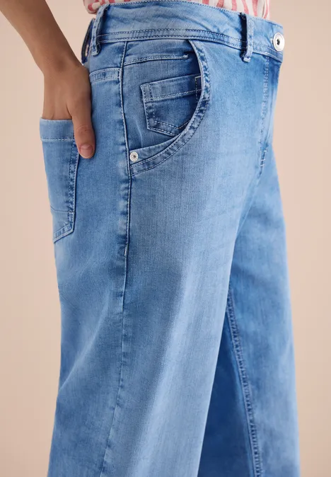 Close-up van een blauwe spijkerbroek met een hand in de zak.