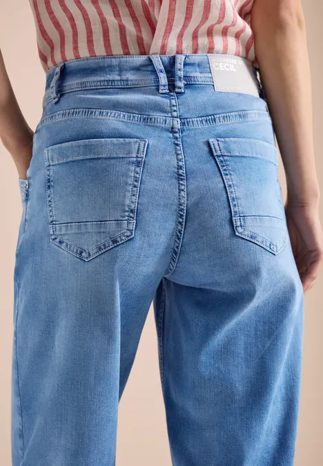 Achteraanzicht van een persoon in lichtblauwe spijkerbroek en rood-wit gestreept topje.