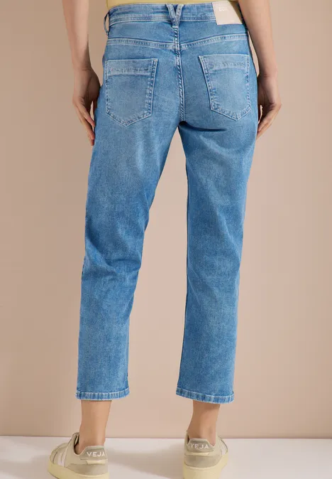 Femme vue de dos portant un jean bleu clair et des baskets beiges