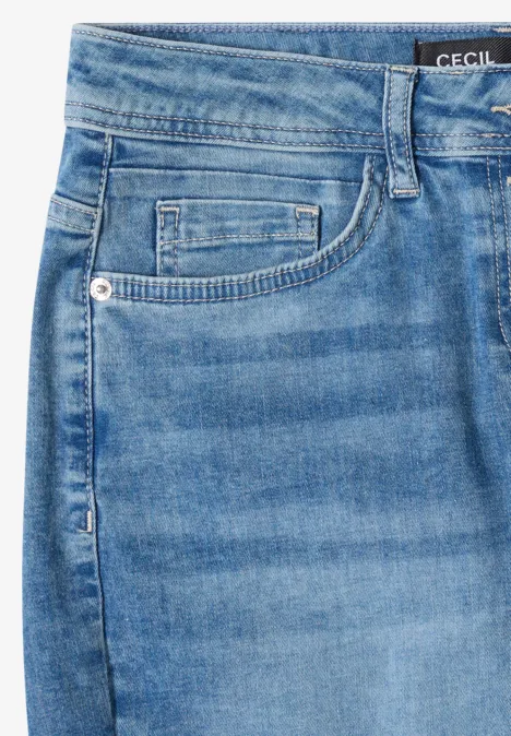 Gros plan d'un jean bleu clair avec poche, passants de ceinture et petite étiquette de marque