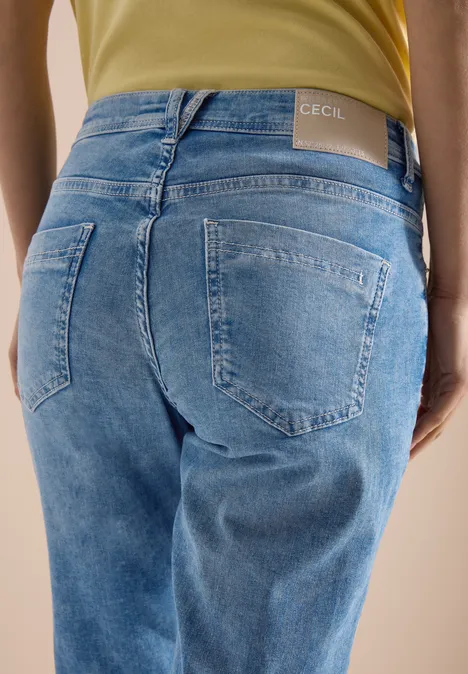 Vue de dos d'une personne portant un jean bleu clair avec étiquette de marque à la taille.
