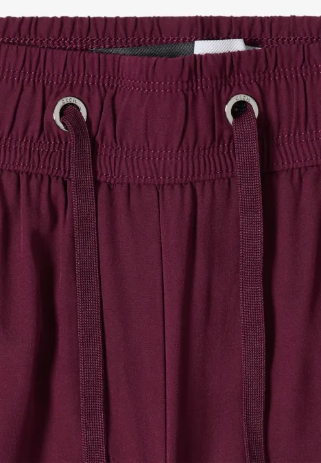 Nahaufnahme von burgunderfarbenen Jogginghosen mit elastischem Bund und Kordelzug.
