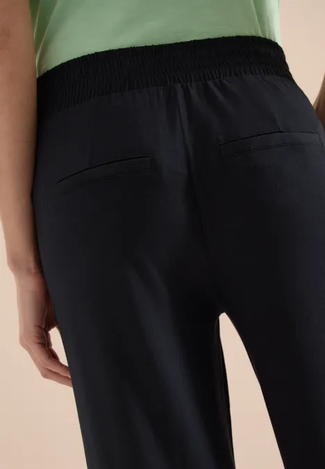 Rückansicht einer Person in dunkelblauen Hosen mit elastischem Bund und aufgesetzten Gesäßtaschen.