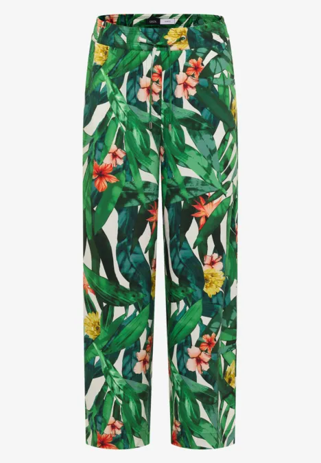 Weite Hose mit tropischem Blumen- und Blattmuster in Grün, Weiß und Rot.