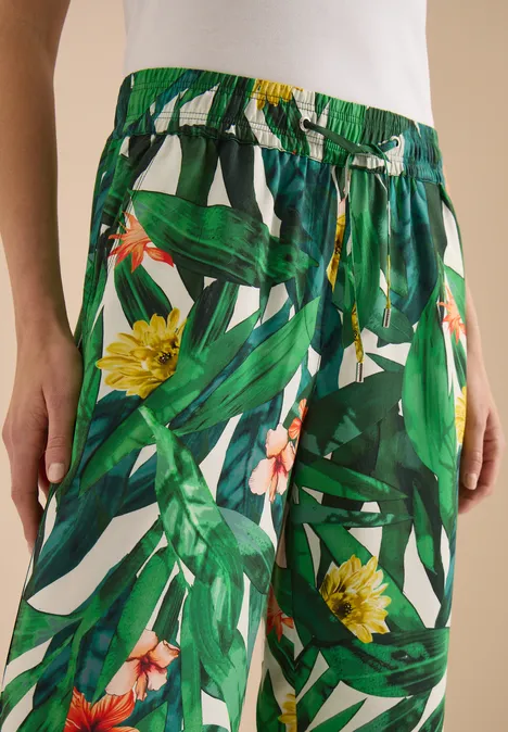 Leichte, weite Sommerhose mit grünem Blatt- und gelbem Blumenprint und Taillenschnürung.
