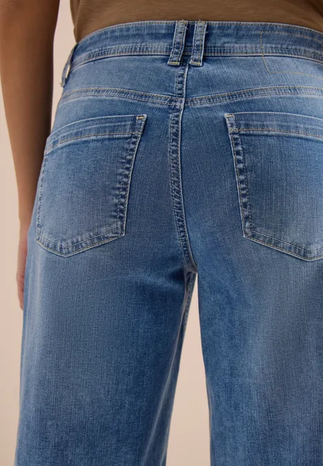 Nahaufnahme einer Person von hinten in lockeren blauen Jeans mit aufgesetzten Gesäßtaschen.