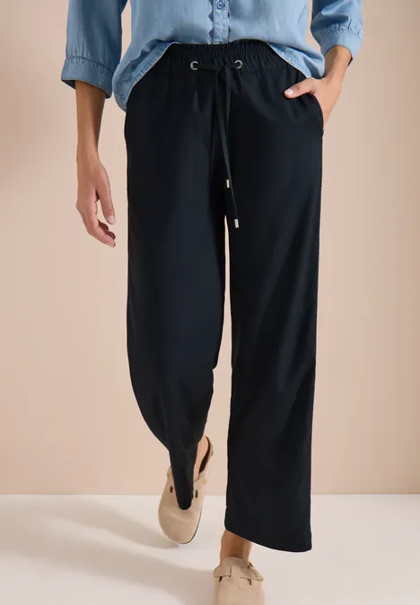 Weit geschnittene, dunkelblaue Damenhose mit Kordelbund und Reißverschlüssen an den Säumen, dazu bequeme Schuhe.