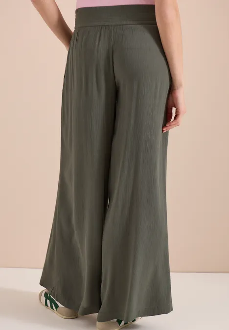 Rückansicht einer Person in olivgrünen, weit geschnittenen, fließenden Highwaist-Hose.