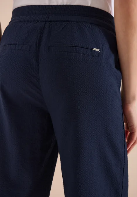 Achteraanzicht van een donkerblauwe, gestructureerde broek met achterzakken en elastische taille.