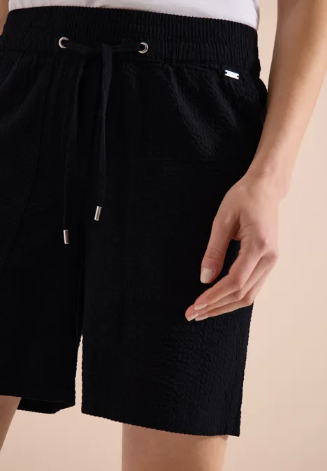 Schwarze, texturierte Shorts mit Tunnelzugbund und Kordel, seitliche Tasche und lockerer Schnitt.