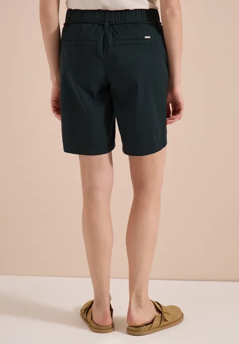 Rückansicht einer Person in schwarzen Bermudashorts und Slippern.