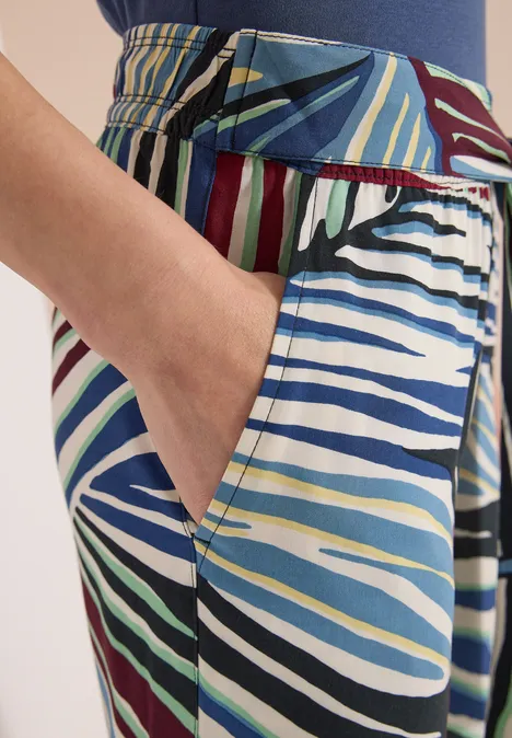 Une main dans la poche d’un pantalon aux rayures colorées et contrastées.