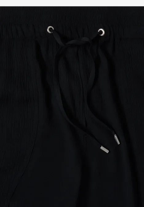 Tissu noir avec cordon de serrage et embouts métalliques argentés dans des œillets.