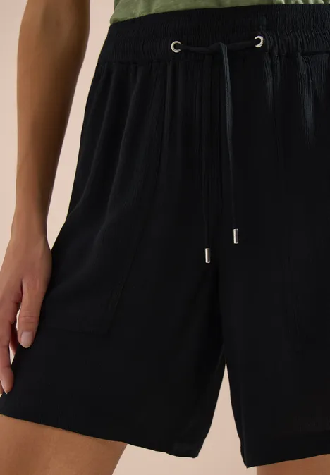 Short noir ample à taille élastique et cordon, poches latérales.