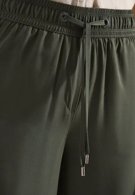 Gros plan d'un pantalon vert foncé avec taille élastique et cordon de serrage.