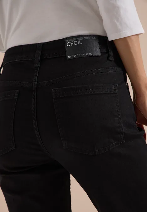 Vue arrière d'une personne portant un jean noir CECIL et un haut blanc.