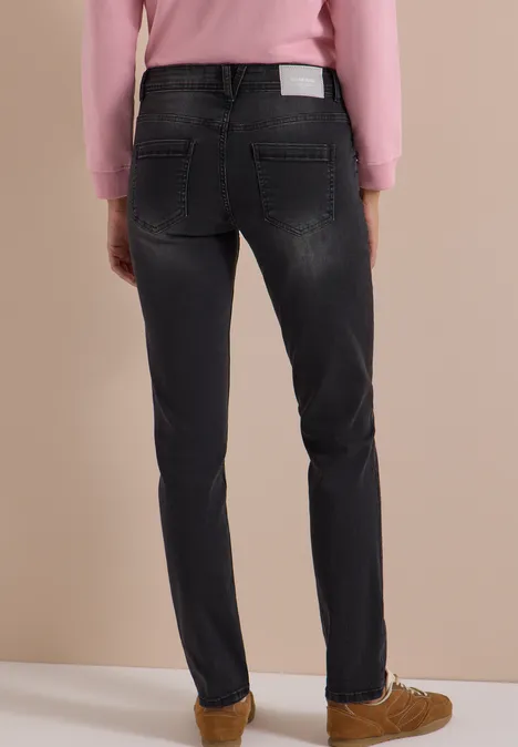 Rückansicht einer Person in dunklen Jeans, rosa Pullover und braunen Schuhen.