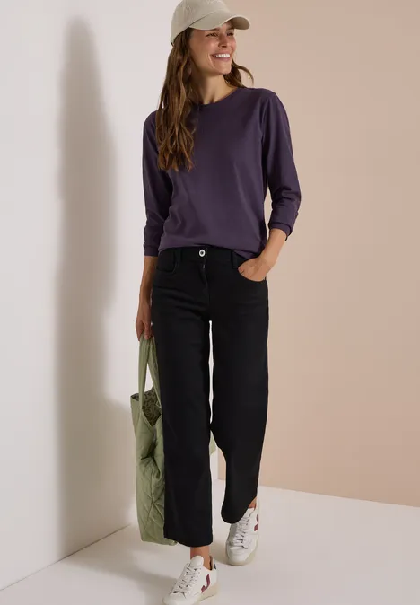 Femme en tenue décontractée avec sac devant un mur