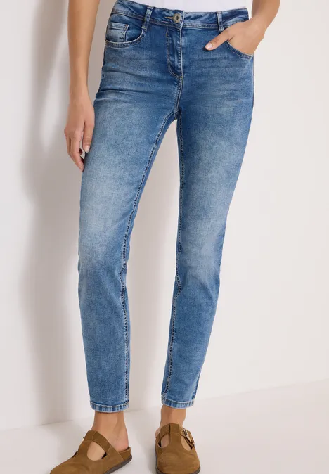 Blaue, eng anliegende Jeans bis zum Knöchel, kombiniert mit braunen Wildleder-Pantoletten.