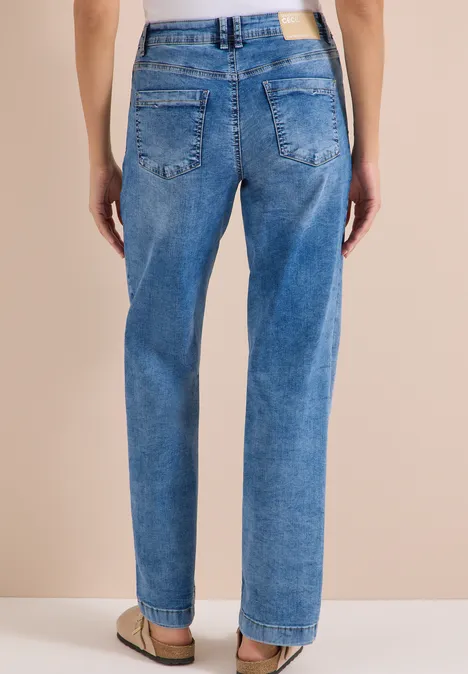 Achteraanzicht van persoon in losse blauwe jeans met zakken en riemlussen.