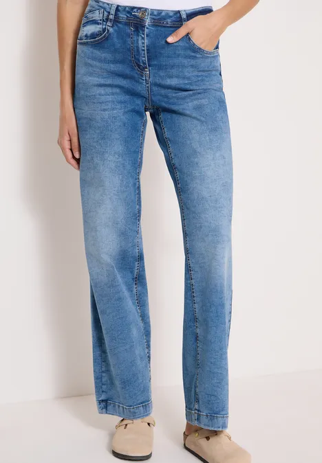 Blauwe damesjeans met hoge taille en rechte pijpen, gecombineerd met lichte sneakers.