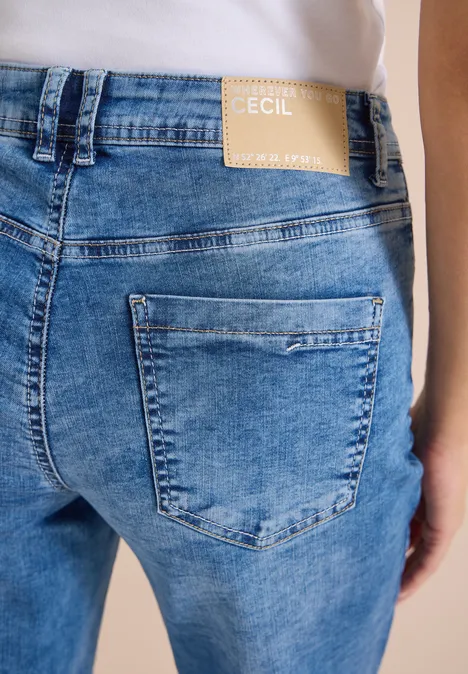 Achteraanzicht van iemand in lichtblauwe jeans met merklabel 'Cecil' op de taille.