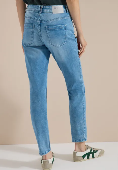 Jean taille moyenne, coupe Slim Leg et style décontracté light blue wash Vue arrière d'une personne portant un jean bleu clair taille haute et des baskets blanches à détails verts.