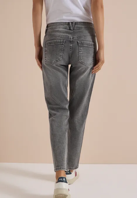 Jeans met Mid Waist-taille en Slim Leg-pijpen in casual pasvorm light grey wash Een persoon van achteren draagt grijze spijkerbroek en witte sneakers tegen lichte achtergrond.