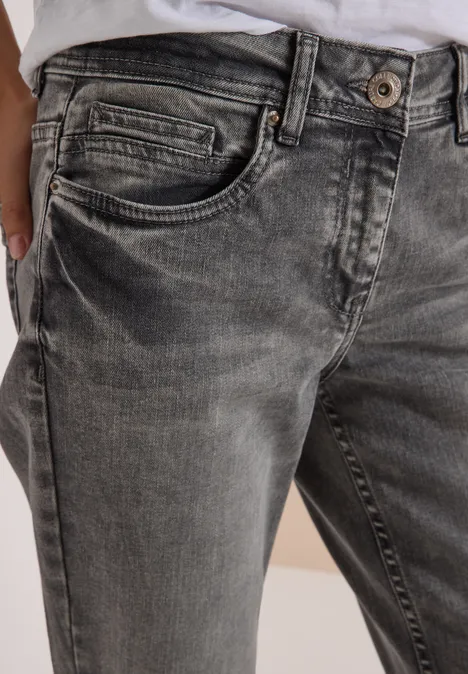 Jeans met Mid Waist-taille en Slim Leg-pijpen in casual pasvorm light grey wash Close-up van grijze, versleten spijkerbroek met zichtbare knoopsluiting en zijzak.