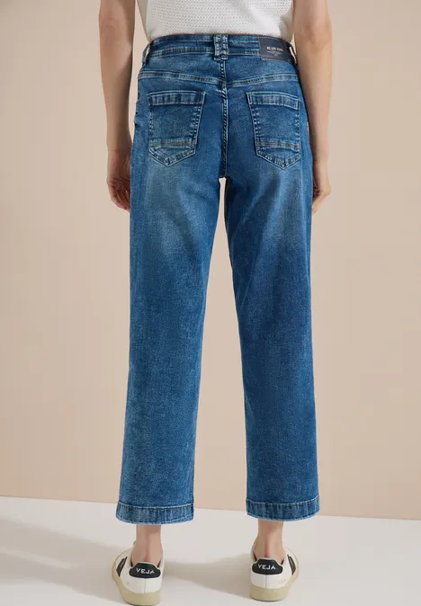 Jean à jambes larges avec des bandes en galon mid blue wash Vue arrière d’une personne portant un jean bleu droit, court et des espadrilles blanches.
