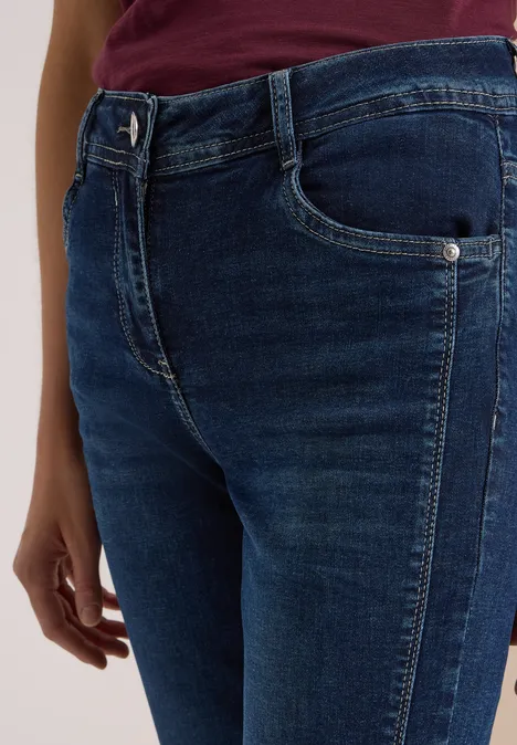 Gros plan sur une femme portant un jean bleu foncé et un haut bordeaux